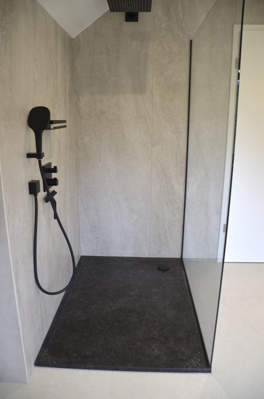 Parois en céramique, tub de douche et évier en pierre bleue